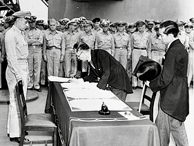 軍関係者が書類に署名している場面、周囲には制服を着た多くの軍人が立っている